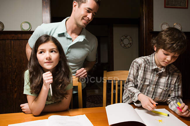 Un padre supervisiona i compiti dei suoi figli — Foto stock