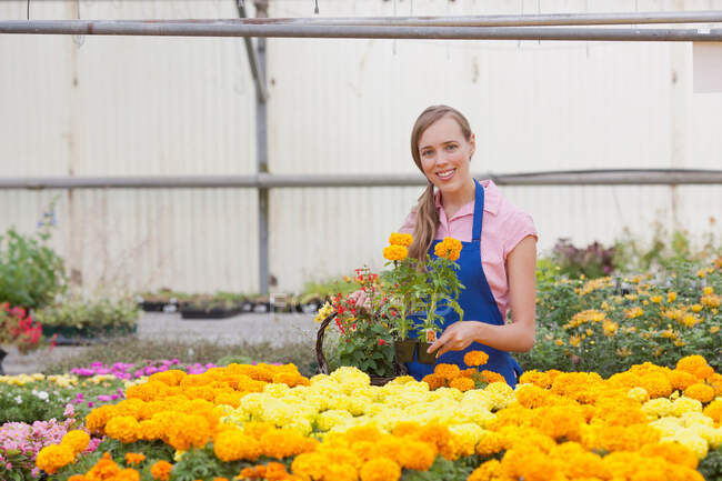 Mitte erwachsene Frau mit Blumen im Gartencenter, lächelnd — Stockfoto