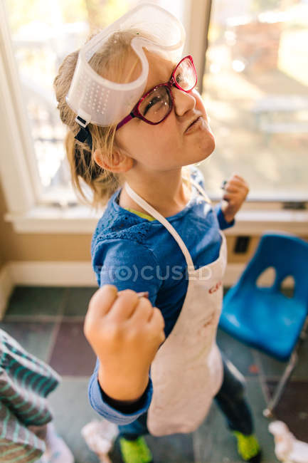 Chica haciendo experimento científico, tirando de una cara y apretando el puño - foto de stock