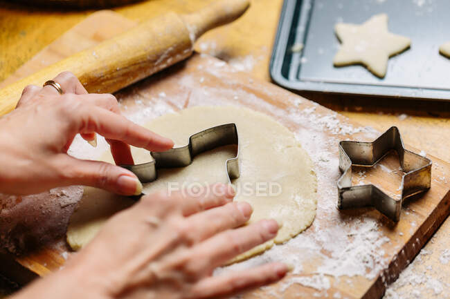 Зрелая женщина прижимает нож для печенья к тесту крупным планом. — стоковое фото