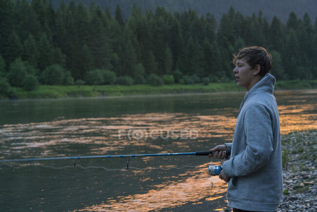 Teenager angelt bei Sonnenuntergang im Fluss, Washington, USA — Stockfoto