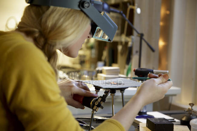 Fabricante de joyas femenino usando soplete miniatura en estudio de diseño - foto de stock
