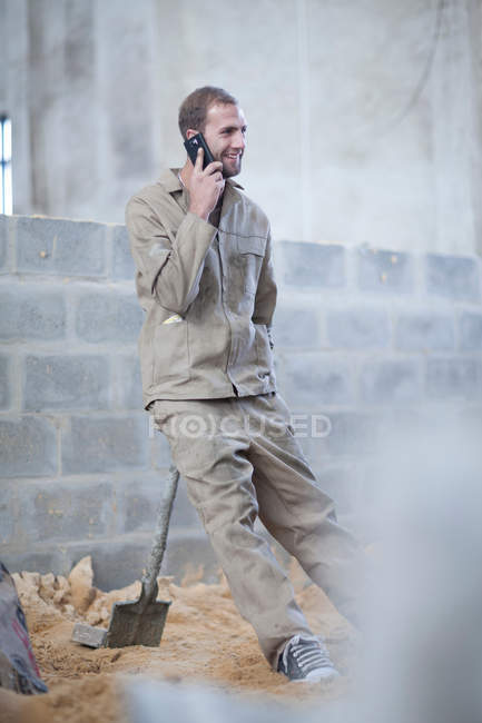 Uomo in piedi con vanga che parla al telefono cellulare — Foto stock