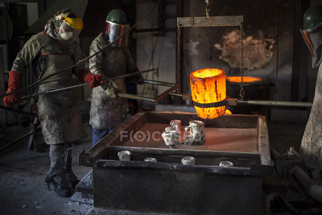 Кейптаун, ЮАР, рабочие в пожарных костюмах готовят бронзу перед литьем — стоковое фото