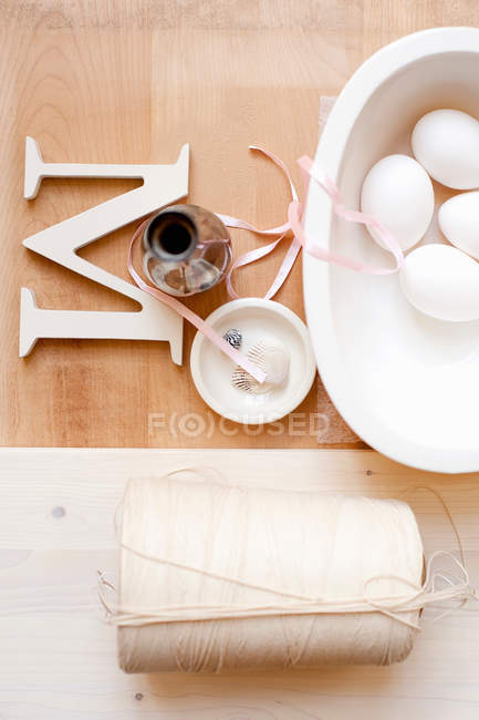 Twine letter M ribbon and eggs in bowl — Stock Photo