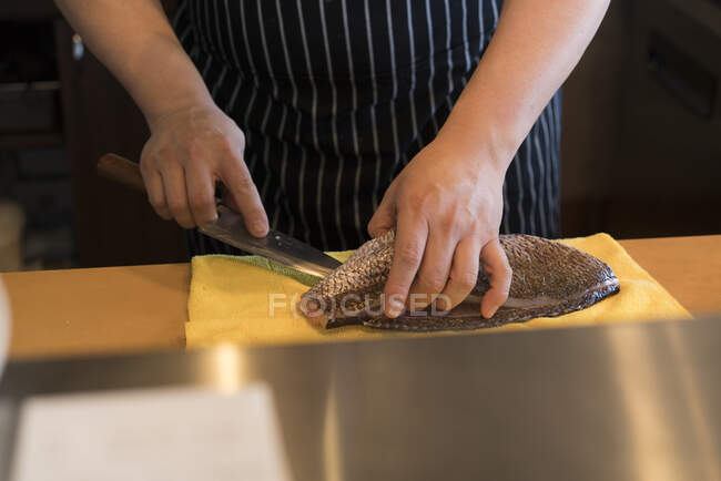 Cropped view of chef in kitchen preparing fish — Stock Photo
