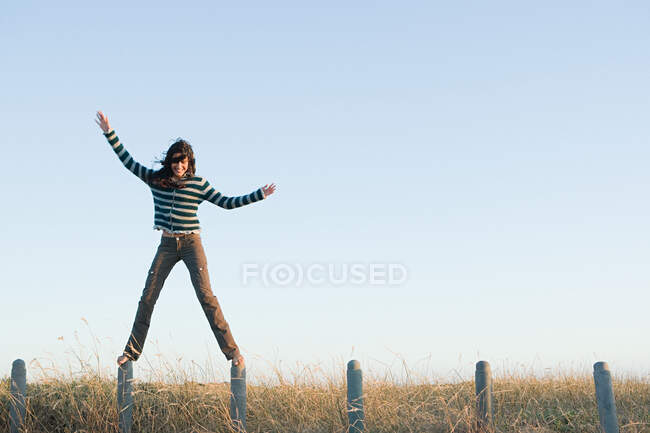 Una donna in equilibrio sui pali della recinzione — Foto stock