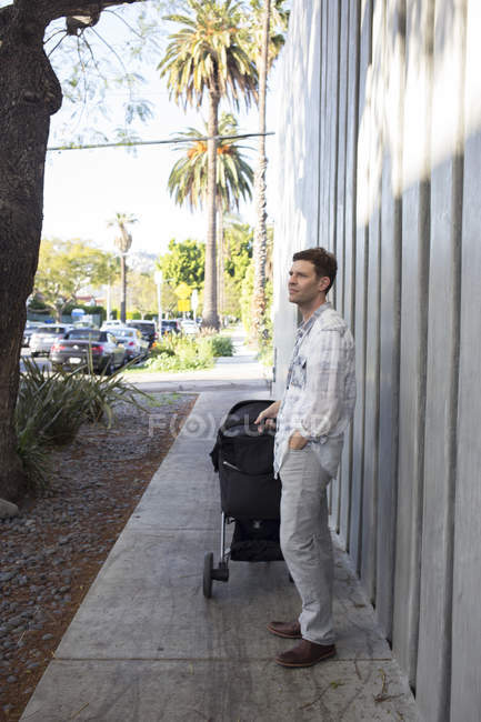 Man pushing baby stroller outdoors — Stock Photo