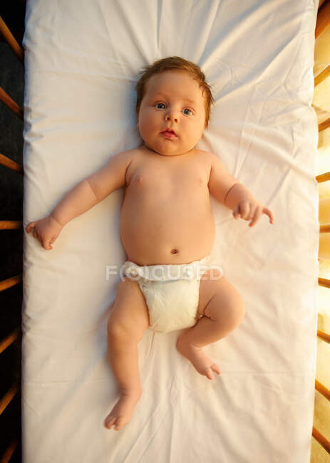 Bebé en pañal / pañal acostado en cuna - foto de stock