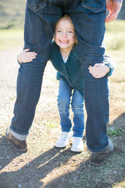 Portrait of girl between father's legs on dirt track — Stock Photo