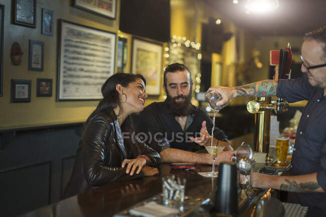 Bartender pouring cocktail for young couple in public house — Stock Photo