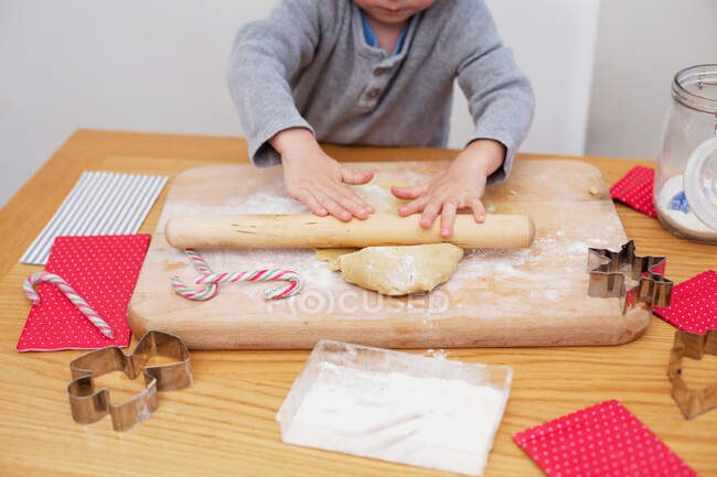 Boy rolling cookie dough, baking Christmas biscuits — Stock Photo
