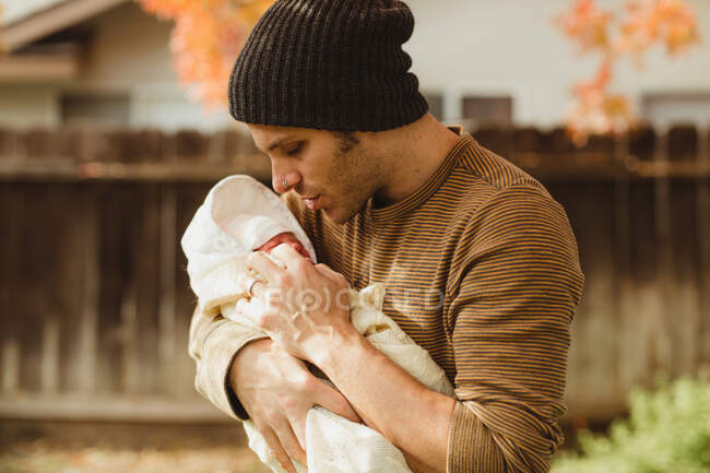 Взрослый мужчина смотрит на новорожденную дочь в саду — стоковое фото
