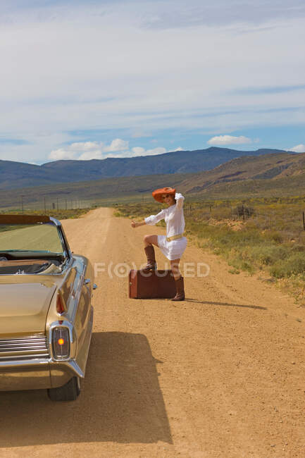 Mulher engatando na estrada do deserto — Fotografia de Stock