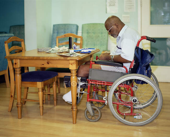Человек в инвалидном кресле катит сигарету — стоковое фото
