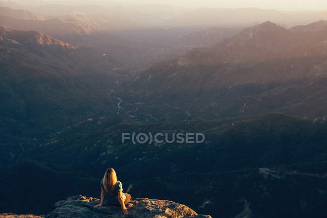 Woman sitting on edge of Moro Rock, Sequoia National Park, California, USA — Stock Photo