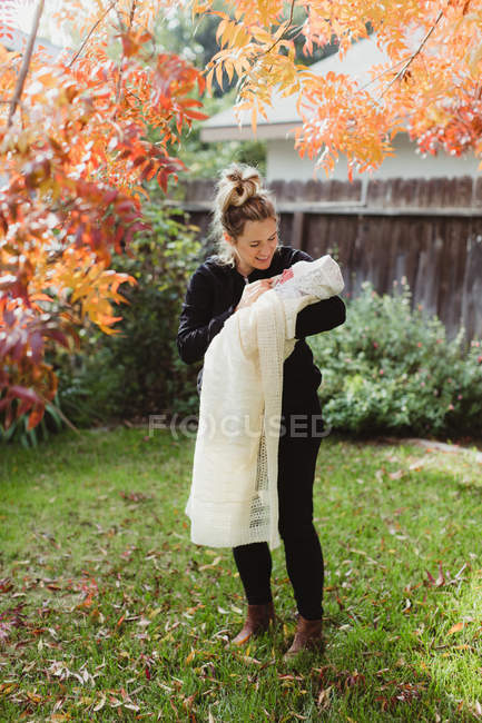 Adult woman carrying newborn baby daughter in garden — Stock Photo