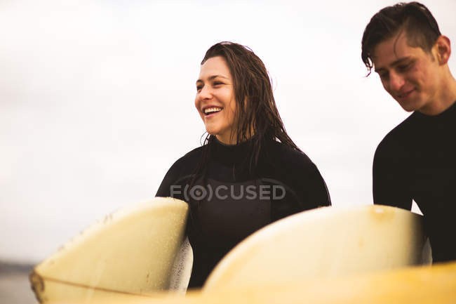 Friends walking away from sea, carrying surfboards — Stock Photo