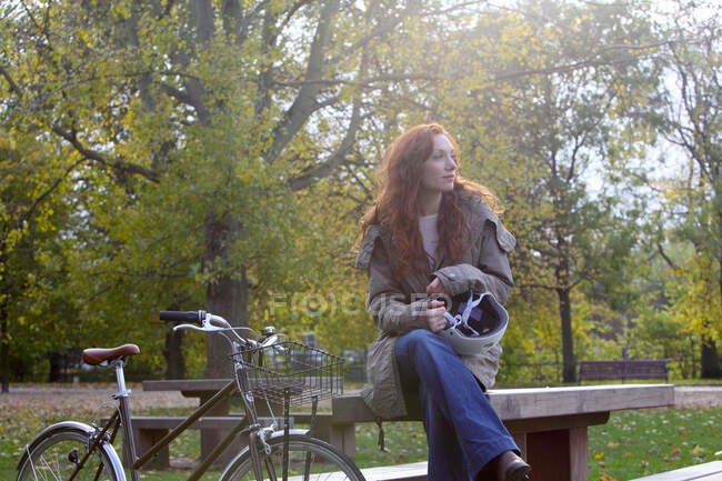 Donna seduta con bicicletta nel parco — Foto stock