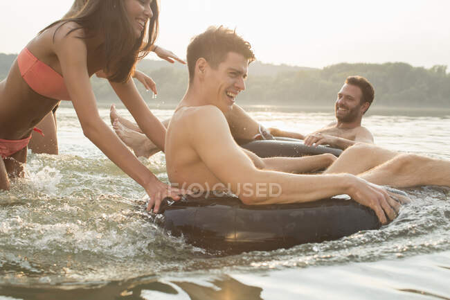 Amici che si divertono con anello gonfiabile nel fiume — Foto stock