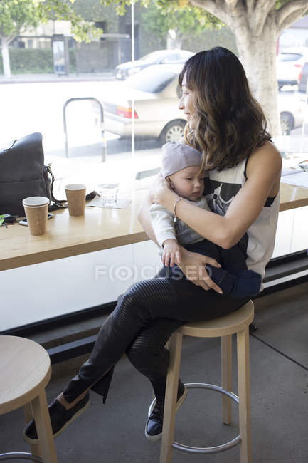 Madre sentada en la cafetería con su hijo pequeño - foto de stock