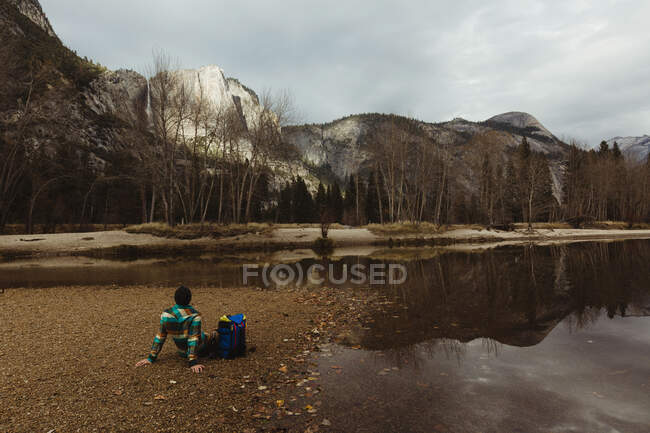 Чоловічий турист сидить біля озера, дивлячись на пейзаж, Національний парк Йосеміті, штат Каліфорнія, США. — стокове фото