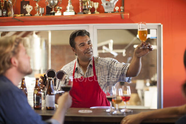 У Кейптауні (Південно - Африканська Республіка) старенький бармен піднімає свій келих для клієнтів, щоб ті оглядали його у броварні. — стокове фото