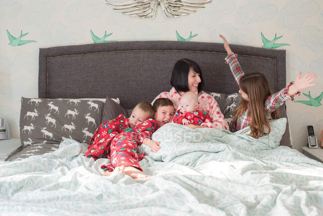 Mãe e filhos deitados na cama juntos — Fotografia de Stock