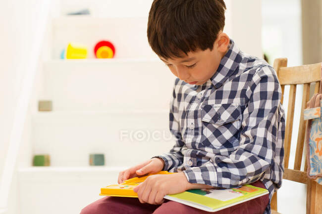 Мальчик сидит на стуле и изучает игру. — стоковое фото