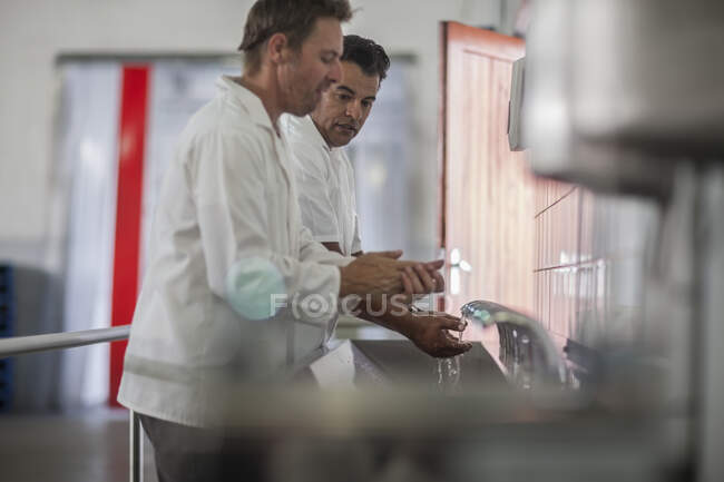 Cidade do Cabo, África do Sul, dois machos na fábrica de embalagens de produção lavar as mãos — Fotografia de Stock