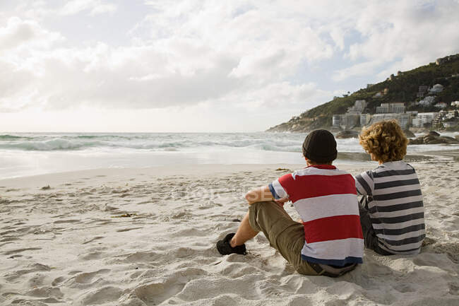 Dos chicos sentados en la playa - foto de stock