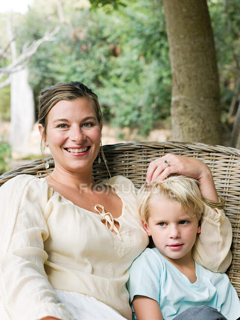 Mother and son sitting on wicker chair, portrait — Stock Photo
