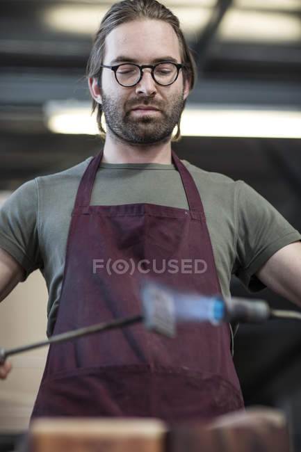 Homem aquecendo ferro de marca com tocha de sopro na fábrica — Fotografia de Stock