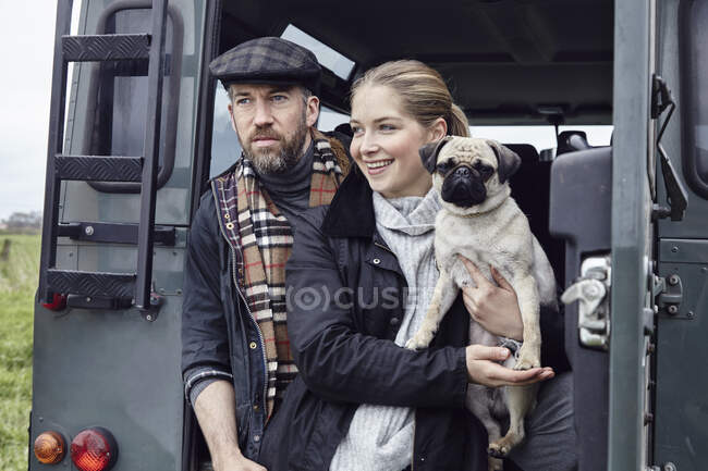 Country couple with dog looking out from back door of off road vehicle — Stock Photo