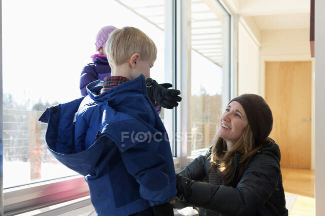 Boy getting dressed in winter clothing, mother helping — Stock Photo
