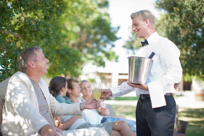 Cameriere servire i clienti in giardino — Foto stock