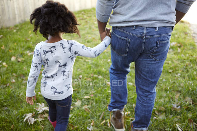 Вид ззаду чоловіка, що йде рукою з дочкою в саду — стокове фото