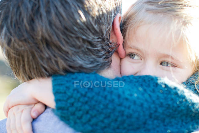 Primer plano por encima de la vista del hombro de la niña abrazando padre - foto de stock