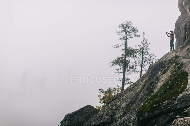 Молодой человек, стоящий на склоне горы, фотографирующий вид, недалеко от озера Шейвер, Калифорния, США — стоковое фото
