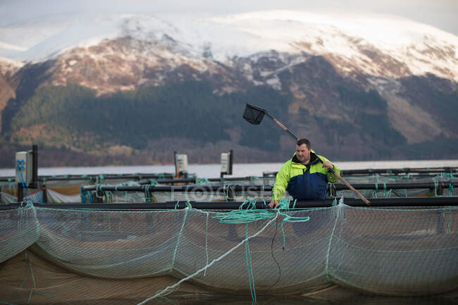 Lavoratore nell'allevamento di salmoni nel lago rurale — Foto stock