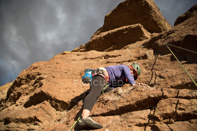 Female rock climber climbing mountain, low angle view, Smith Rock State Park, Oregon, USA — Stock Photo