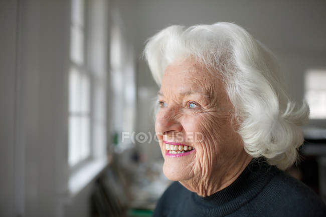 Portrait of senior woman looking out of window — Stock Photo