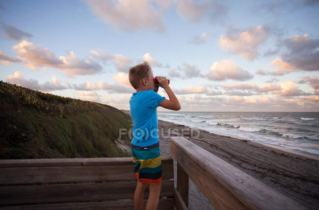 Boy at beach looking at view through binoculars, Blowing Rocks Preserve, Jupiter, Florida, USA — Stock Photo