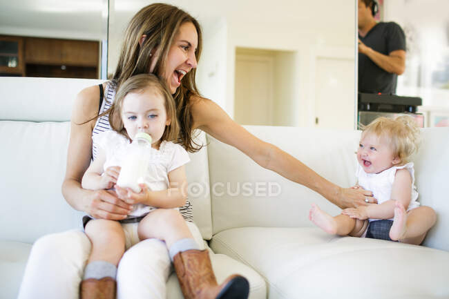 Female toddler on mother's lap drinking from baby bottle — Stock Photo
