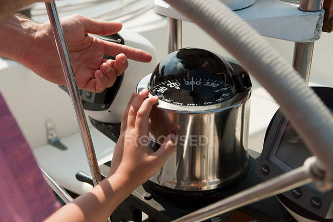 Father and son on board yacht, father pointing to speedometer — Stock Photo