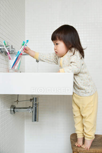 Ragazza bambino in punta di piedi raggiungendo oltre lavello del bagno — Foto stock