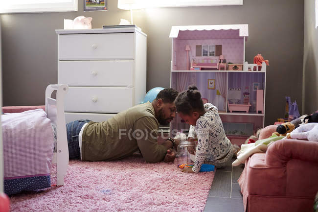 Padre e hija jugando junto a su casa de muñecas - foto de stock