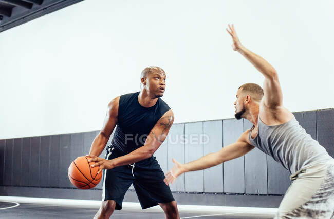 Dos jugadores de baloncesto practican la defensa de pelota y apuntan a la cancha de baloncesto - foto de stock