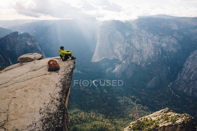 Homem sentado no topo da montanha, com vista para o Parque Nacional de Yosemite, Califórnia, EUA — Fotografia de Stock