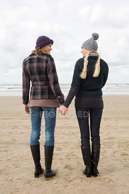 Women holding hands by the sea — Stock Photo